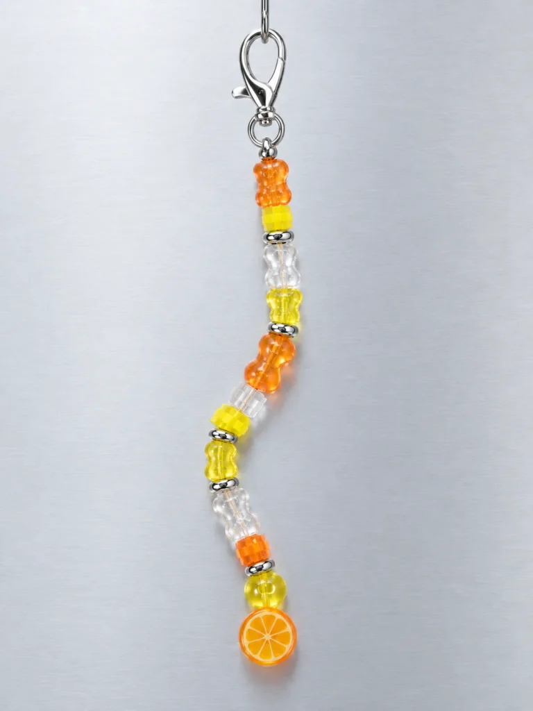 Tangerine Glitch Earbud Case Charm hanging from its clasp